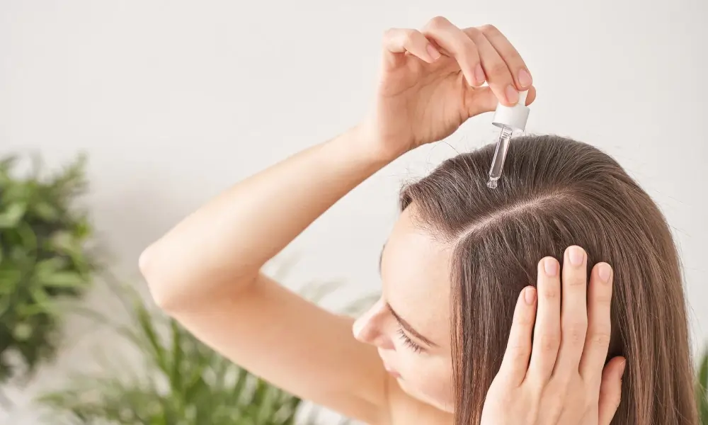 a girl pouring oil in her hair